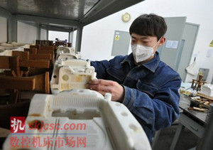图为699厂职工在修理3D打印机生产出的蜡模